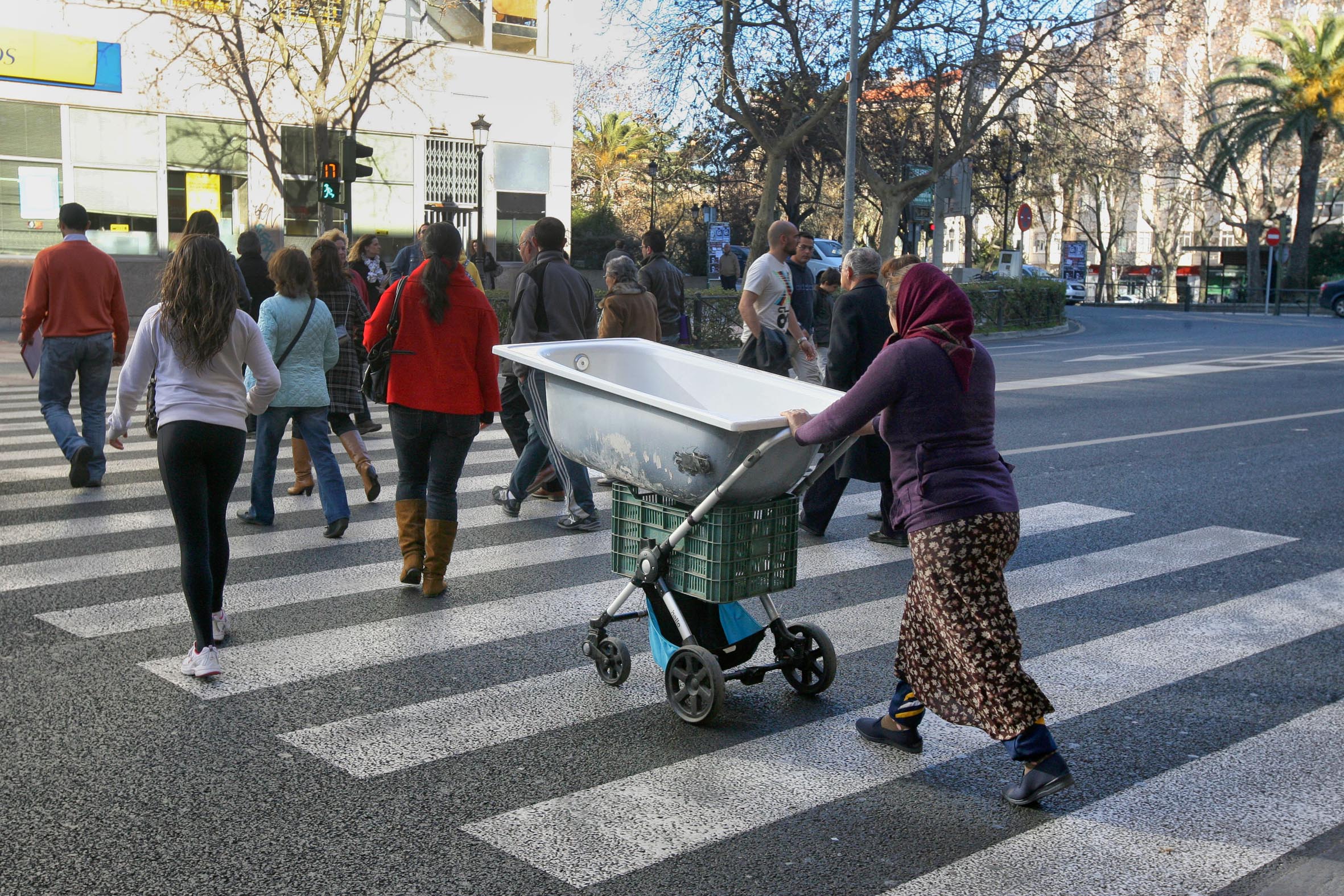 Una mujer utiliza un carrito de niño para trasladar una bañera por las calles céntricas de Cácer3es.