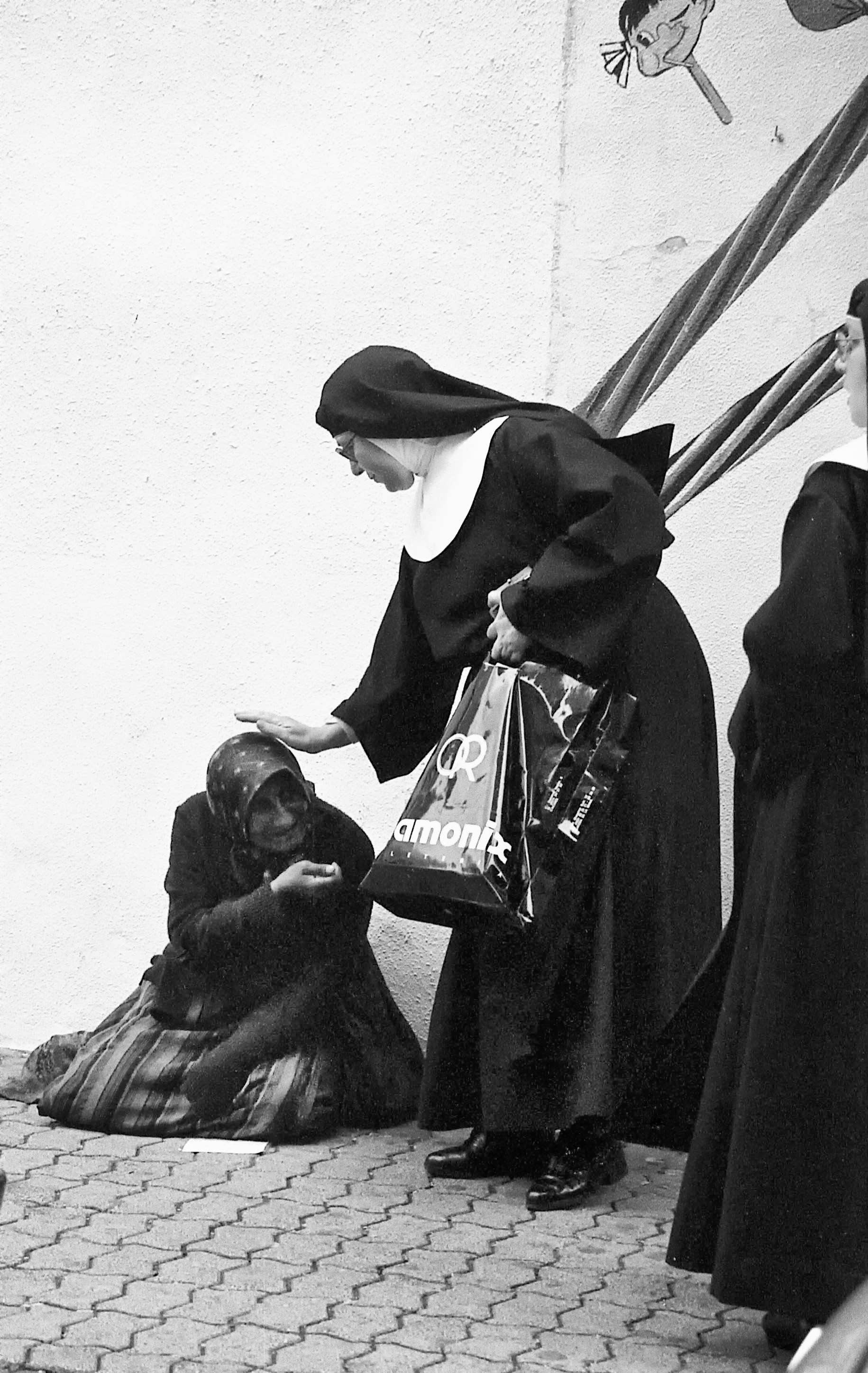 Una monja acaricia con cariño la cabeza de una mendiga en la calle San Pedro (1989).