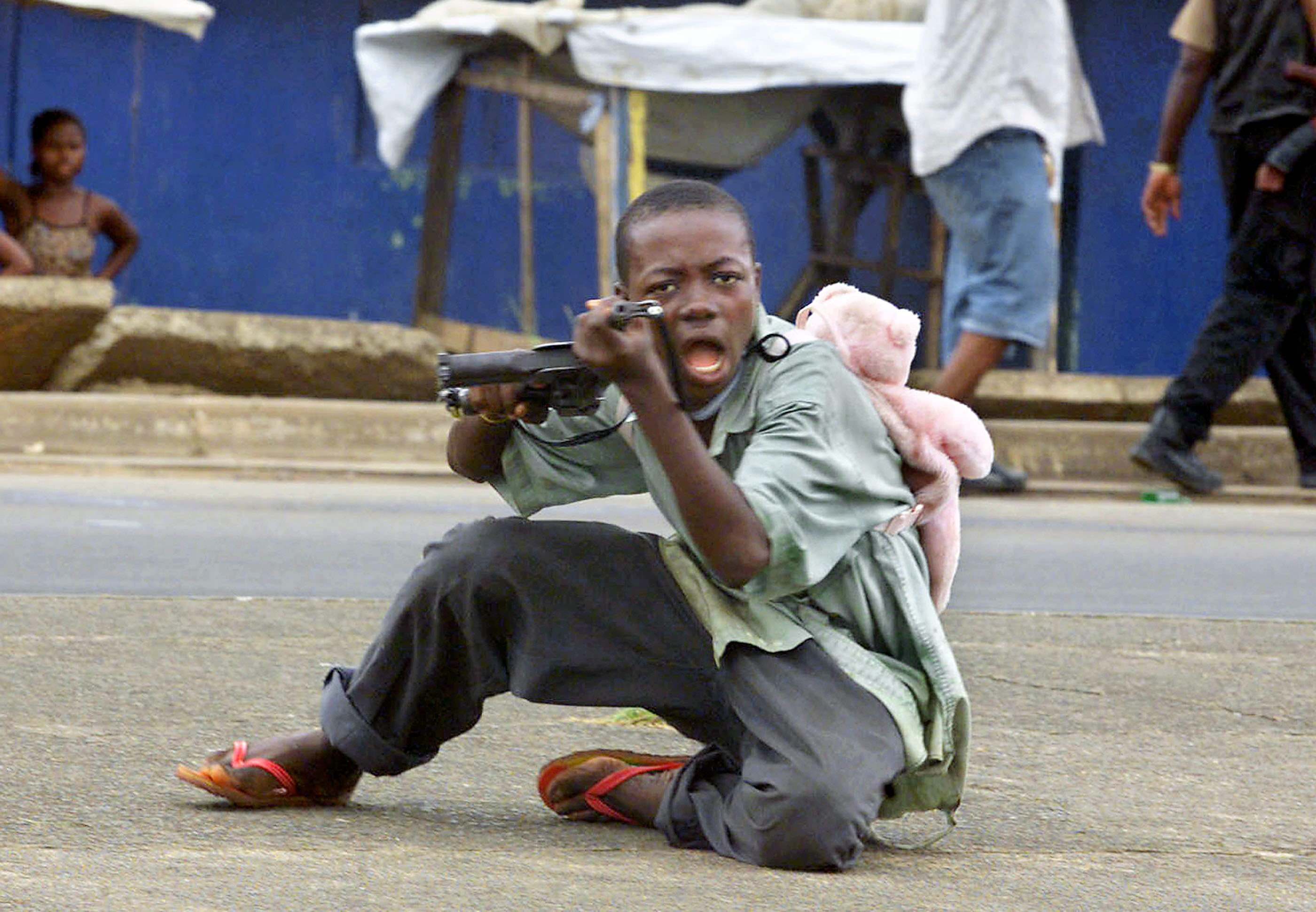 LIBERIA-CHILD-SOLDIER-TEDDY BEAR Un niño soldado liberiano, con un osito de peluche a la espalda, apunta con su arma a un fotógrafo en una calle de Monrovia. AFP